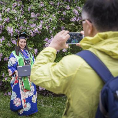 一名身着彩色毕业礼服的学生让父母给他们拍照.