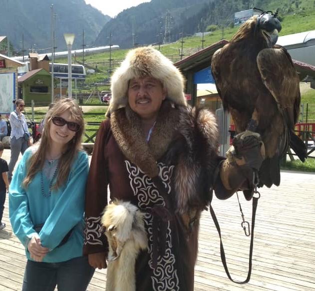在哈萨克斯坦的阿拉木图附近，20岁的凯瑟琳·康奈尔(Kathleen Connell)与一位哈萨克鹰猎人站在一起