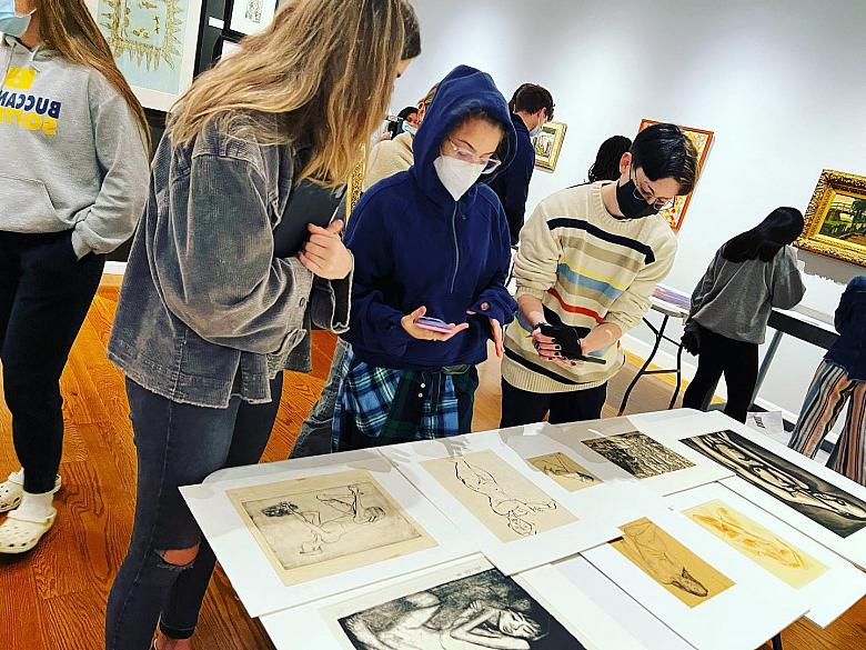 Students look at artwork on a table in the Wright Museum of Art.