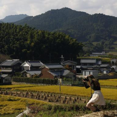 A student photographs of a luscious and green countryside landscape in rural Japan with a profess...